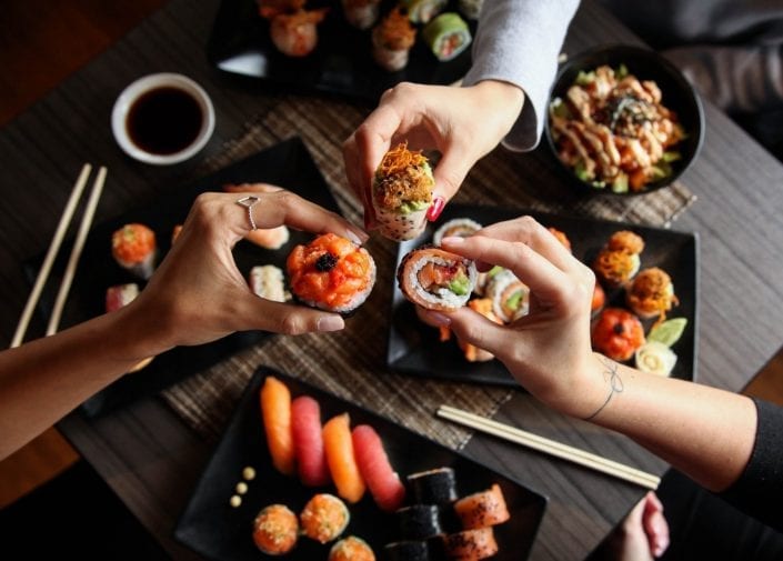 Trois personnes partageant des assiettes de sushis